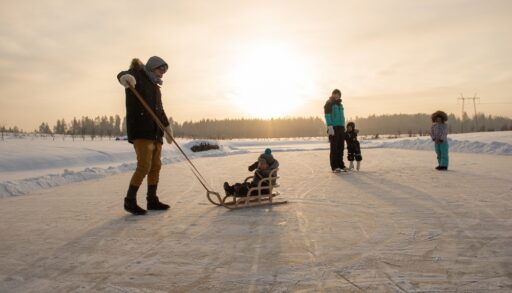 Family skating on an outdoor rink at sunset.