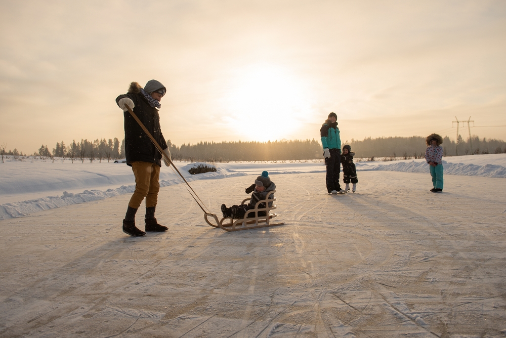 Family skating on an outdoor rink at sunset.