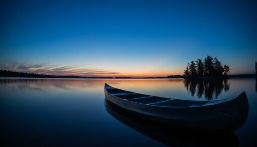 A canoe on a still lake at sunset.