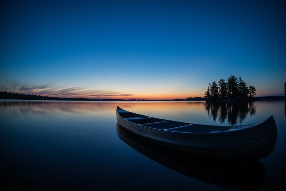 A canoe on a still lake at sunset.