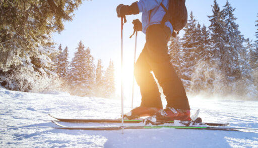 Close-up of a person wearing red ski boots and skiing on a snow-covered hill.