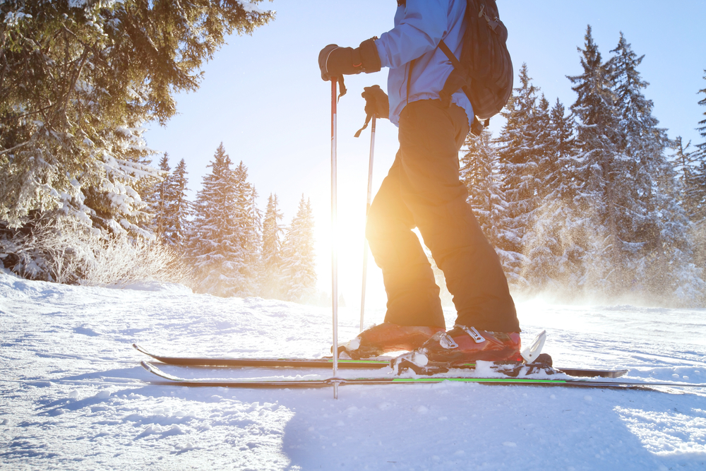Close-up of a person wearing red ski boots and skiing on a snow-covered hill.