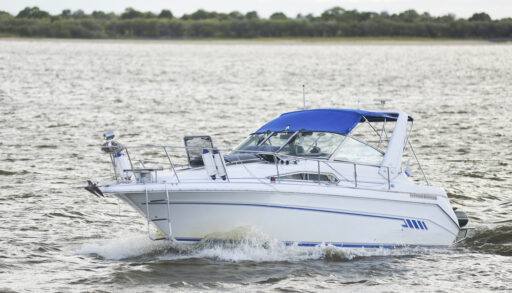 A white and blue yacht speeding across a lake.