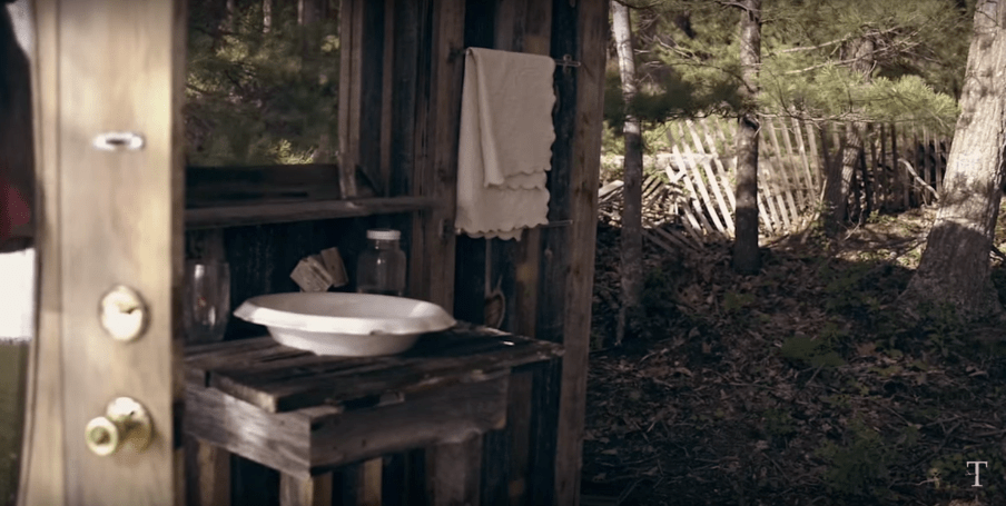 A basin and towel on in front of a wooden wall outdoors