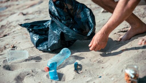 Person picking up trash on a beach.