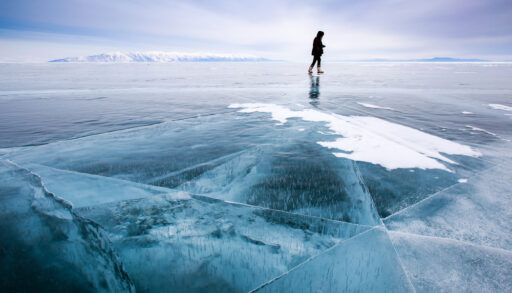 Person skates on blue frozen lake.