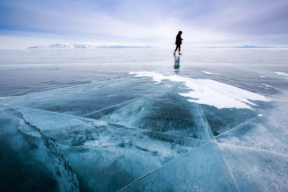 Person skates on blue frozen lake.