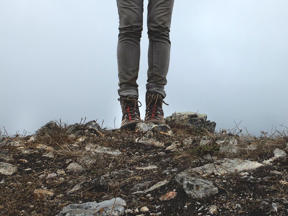Person's legs in hiking boots standing on hiking trail
