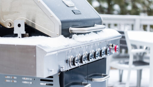 Outdoor grill covered with snow on back patio in the winter