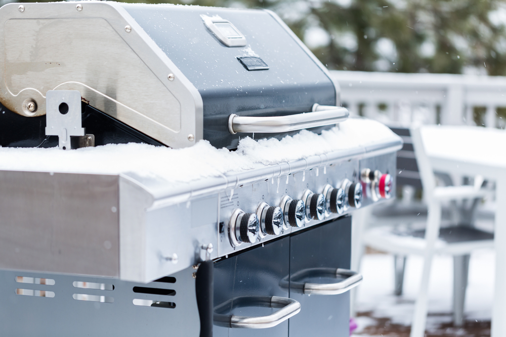 Outdoor grill covered with snow on back patio in the winter