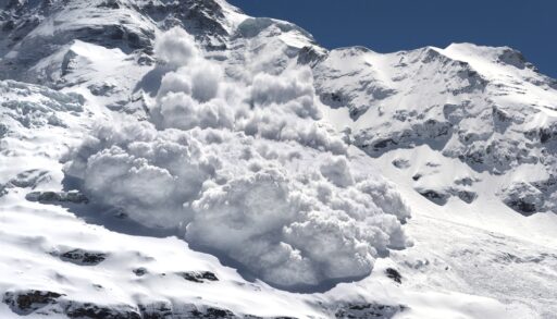 Avalanche of snow rumbling down a steep mountain.