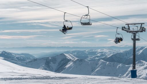 Skiers and snowboarders riding chair lift at a winter resort.