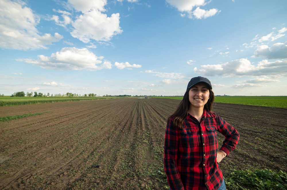 Farmer in red plaid shirt standing in a field.