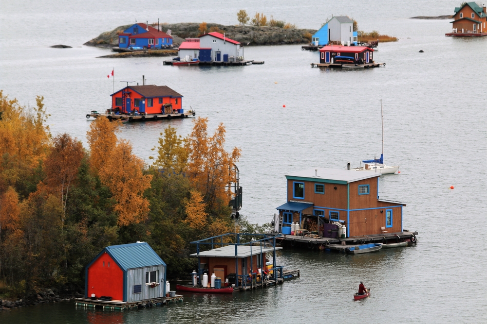 Colorful house boats floating on a lake that has the occasional tree in autumn.