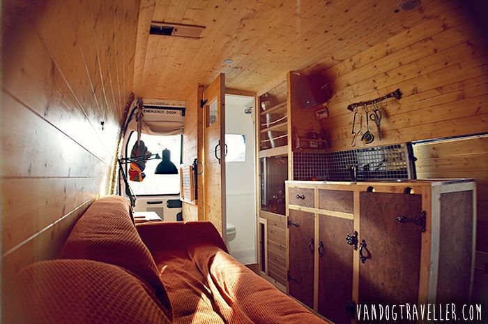 Interior of camper van with couch, sink, and bathroom