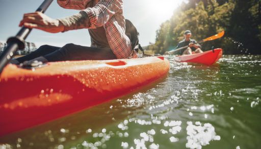 Close-up of two people canoeing on a sunny lake.