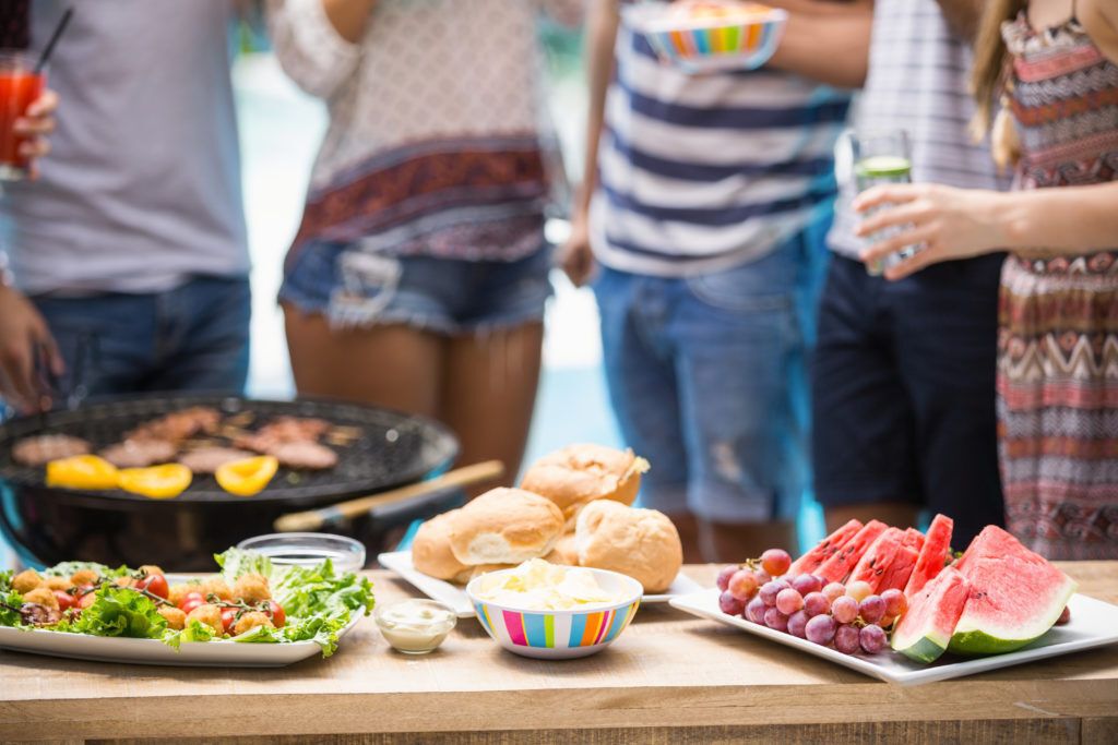 A group of people standing around a table with food.