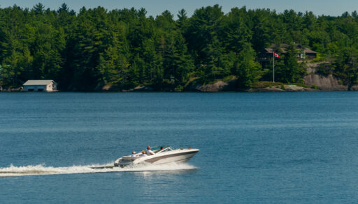 A white motor boat speeding across Lake Muskoka, Ontario.