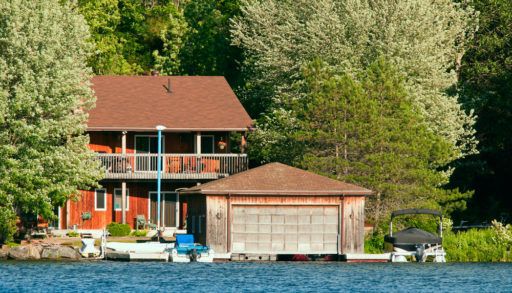 Cabin nestled in a forest overlooking a lake.