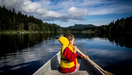 Little kid sitting in a canoe, paddling.