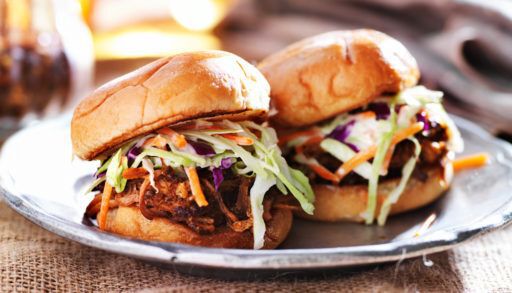 Beef sliders with a green slaw on a white plate.