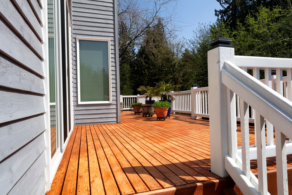 Wooden deck with a white railing attached to a blue house.
