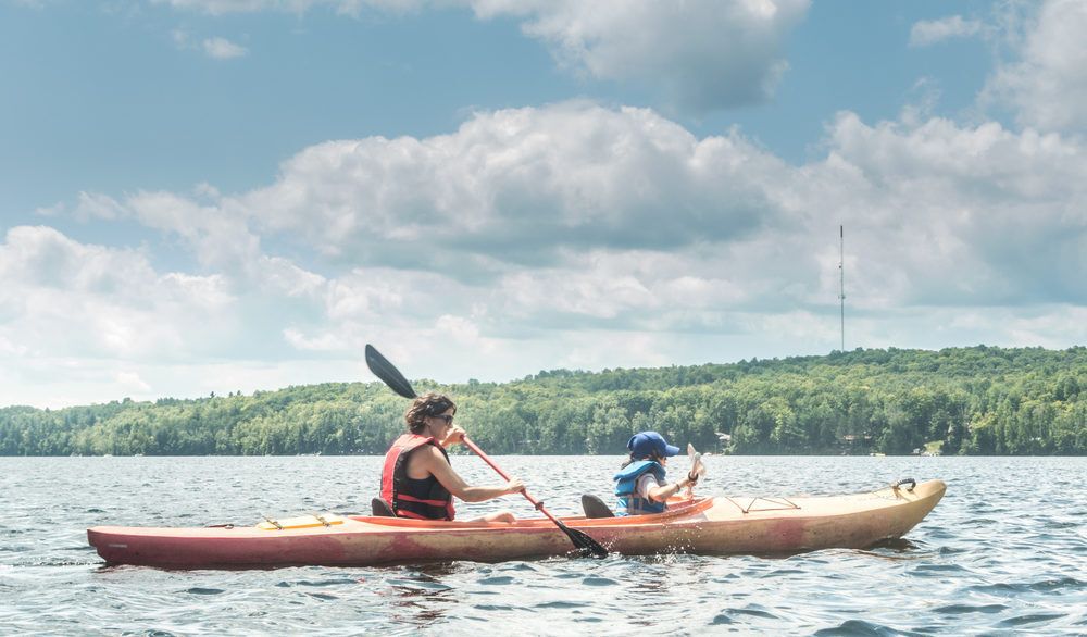 A woman canoeing with her kid on a lake.