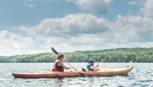 A woman canoeing with her kid on a lake.