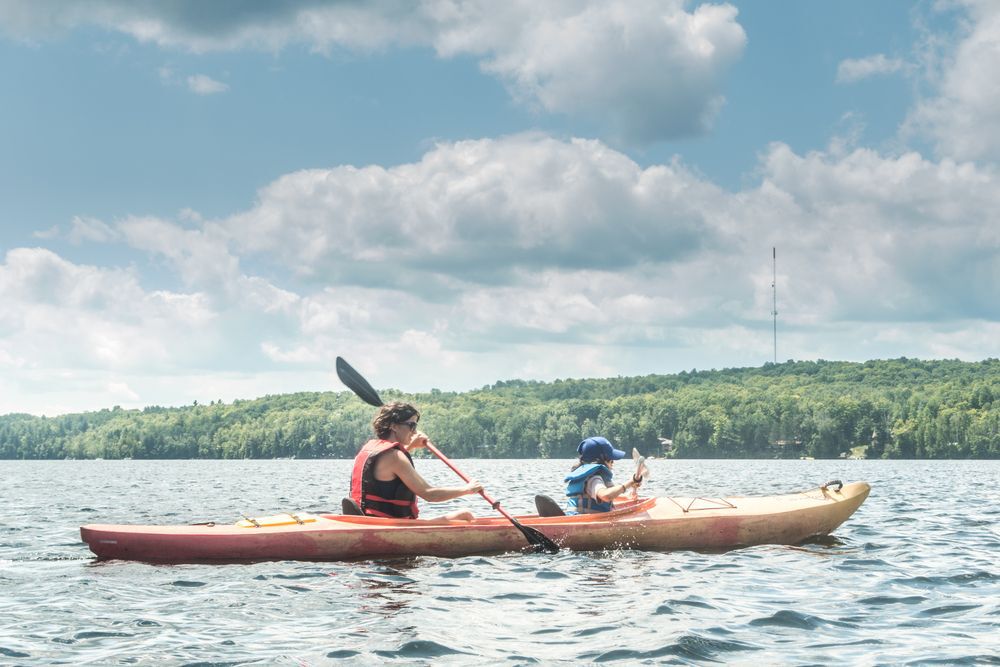 A woman canoeing with her kid on a lake.