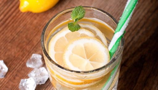 Cocktail with lemon slices floating in it sitting on a wooden table.