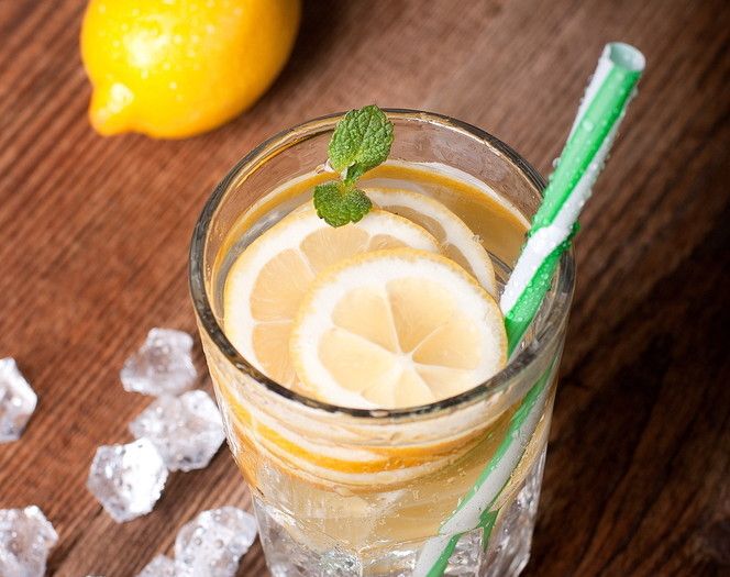 Cocktail with lemon slices floating in it sitting on a wooden table.
