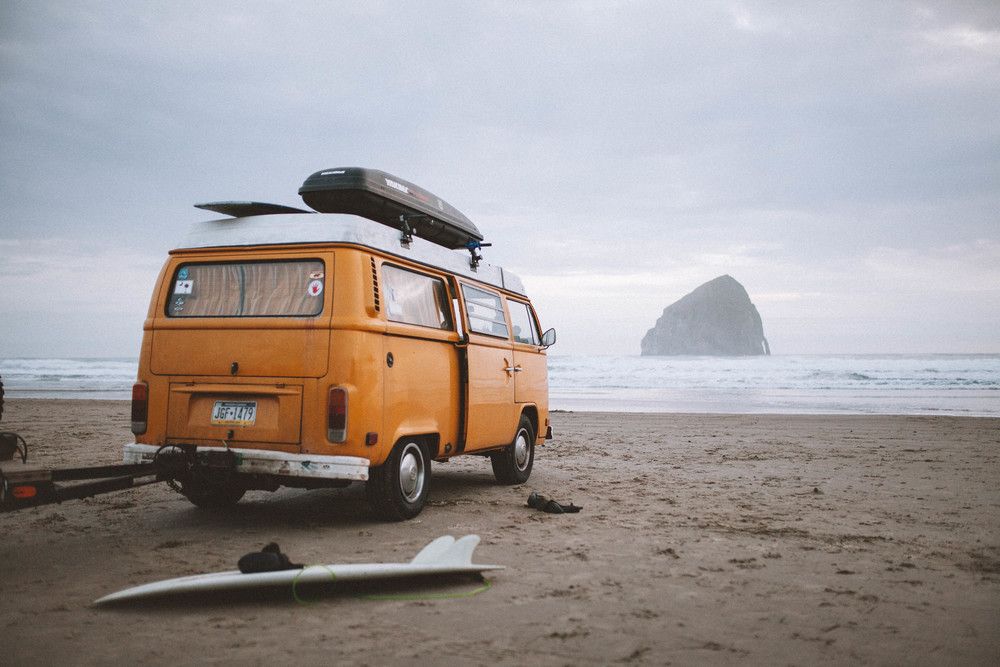 VW van in front of water, with surfboards