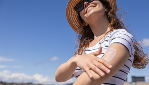 A woman applying sunscreen to her arm.