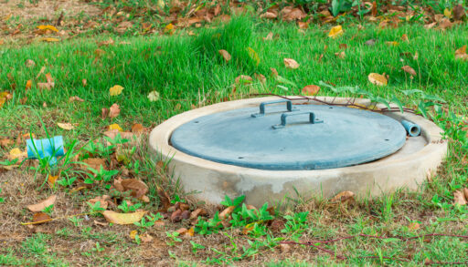 Close-up of a green septic tank lid in a grassy field.