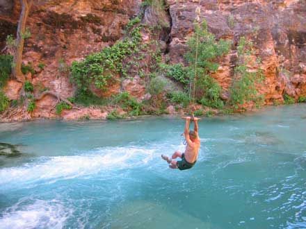 Older man swinging into blue water