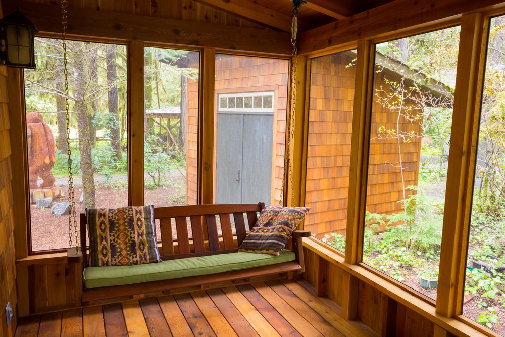 Wooden screened-in porch with a bench swing.