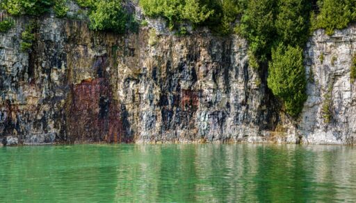 Green and rocky cliffs and calm waters of Elora Quarry Ontario, Canada.