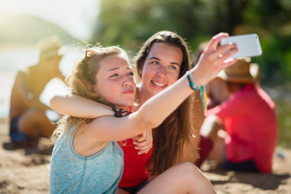 Two teen girls taking a selfie on a beach.