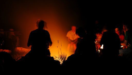 Silhouettes of people sitting around a campfire.