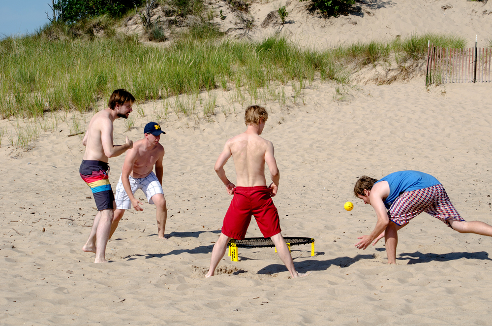 Guys playing spike ball on the beach.