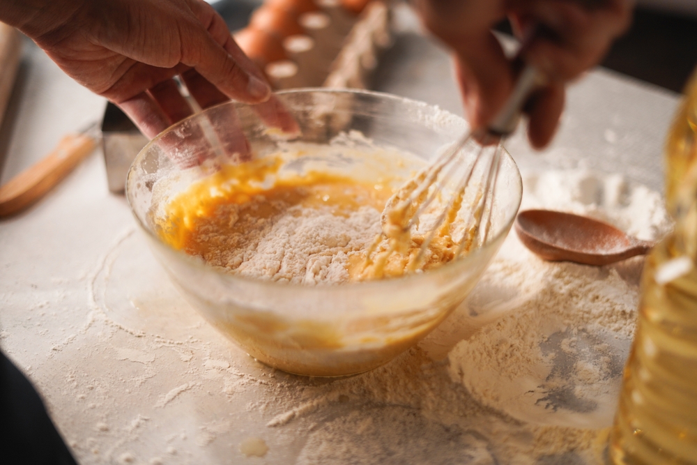 Person whisking ingredients together in a bowl.