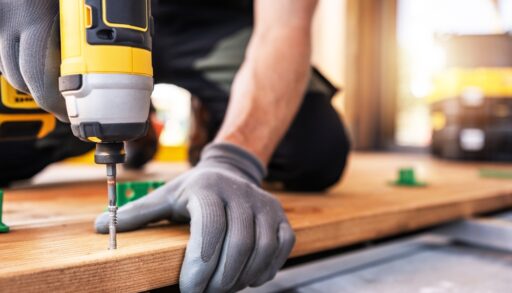 Person drilling a screw into a wooden board.