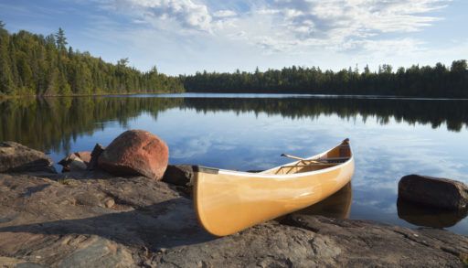 Wooden canoe on the rocky shore of a lake.