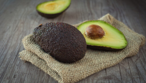A halved avocado on a beige cloth.