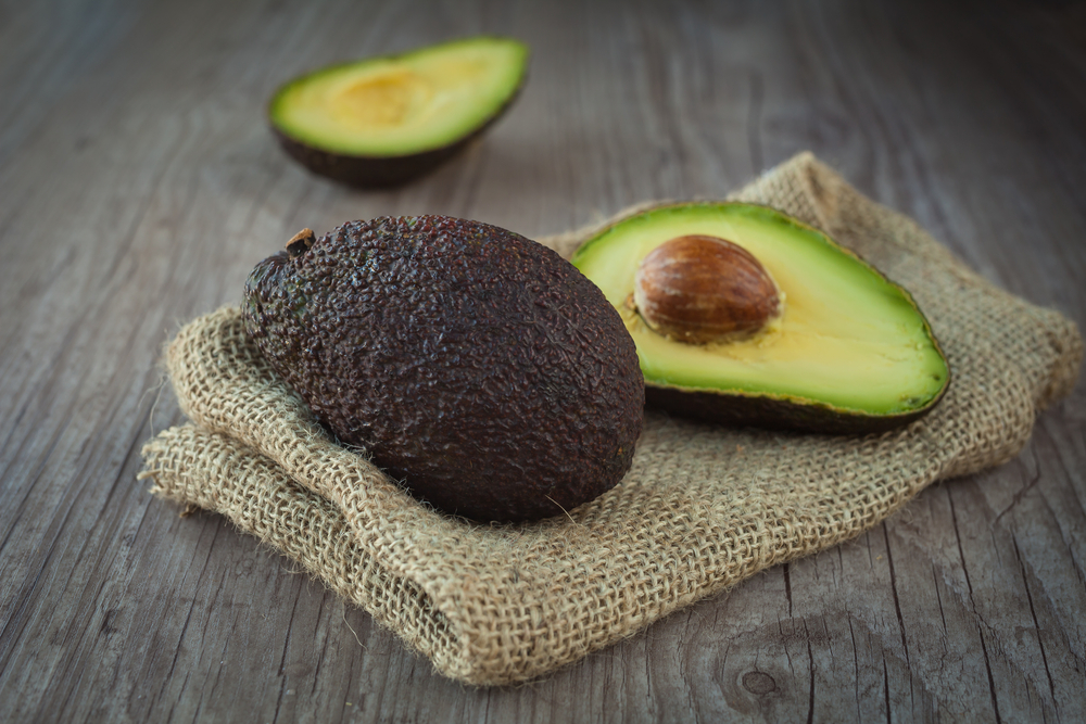 A halved avocado on a beige cloth.