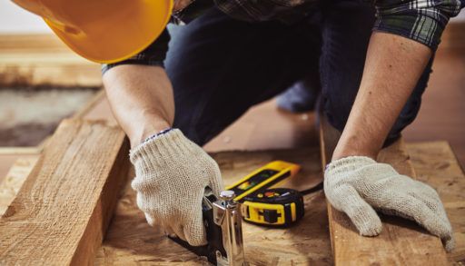 Man in a yellow construction helmet woodworking.