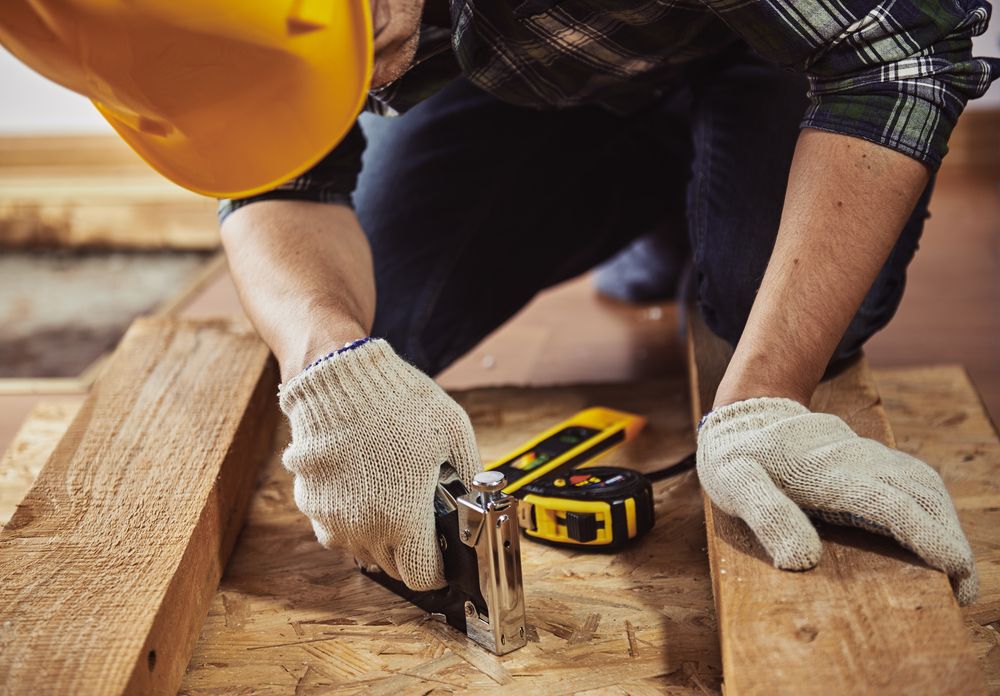 Man in a yellow construction helmet woodworking.