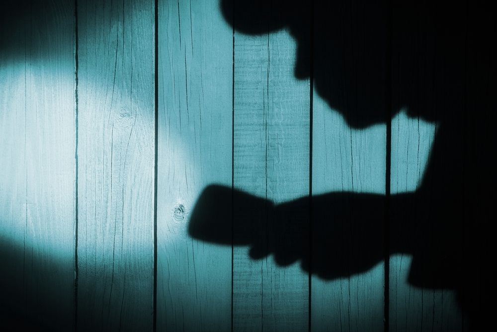 Shadow of a burglar holding a flashlight.