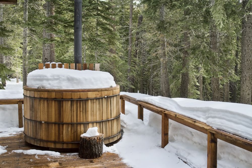 Wooden hot tub outside covered with snow in the winter.