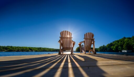 Sunrise creating shadows of two chairs on a dock in summer.